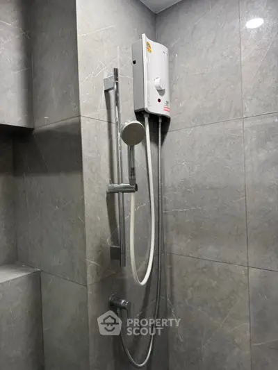 Modern bathroom with sleek shower fixtures and gray tiled walls.