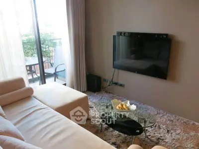 Modern living room with cozy seating and wall-mounted TV, overlooking a balcony with greenery.