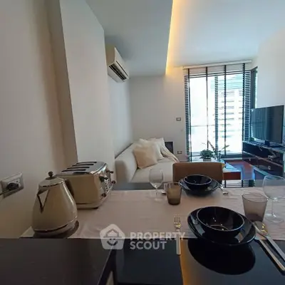 Modern living room with sleek furniture and dining setup, featuring a cozy sofa and large TV near a bright window.