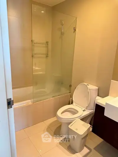 Modern bathroom with glass shower and sleek fixtures in contemporary apartment.