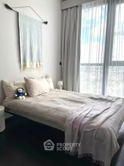 Cozy bedroom with large window and stylish decor, perfect for relaxation and comfort.