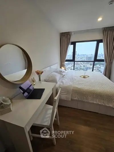 Modern bedroom with city view, featuring a cozy bed, desk, and large window for natural light.