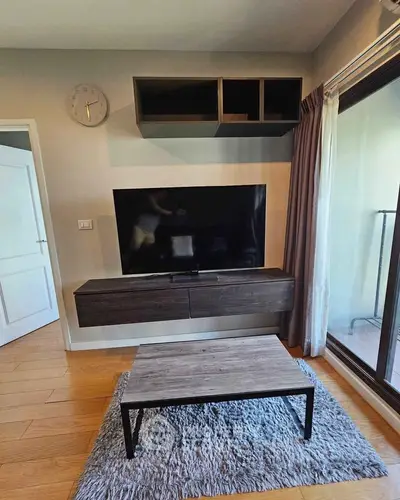 Modern living room with wall-mounted TV, sleek furniture, and large window for natural light.