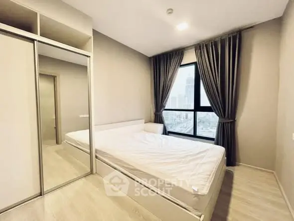 Modern bedroom with large window and mirrored wardrobe in a high-rise apartment.
