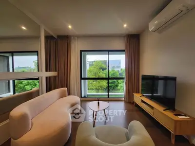 Modern living room with stylish furniture and large window offering a lush green view.