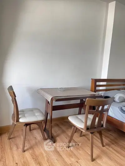 Cozy bedroom with wooden furniture and small dining table, perfect for compact living spaces.