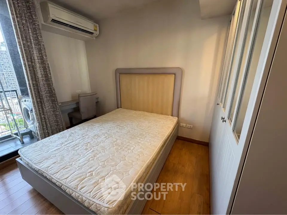 Modern bedroom with balcony view in urban apartment, featuring air conditioning and stylish decor.