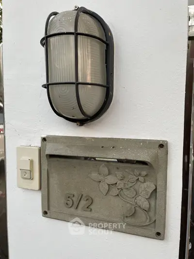 Charming exterior wall with vintage light fixture and decorative address plaque.