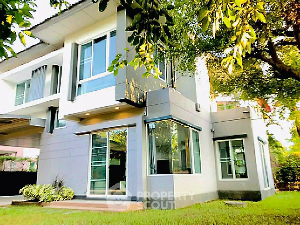 Modern two-story house with large windows and lush greenery
