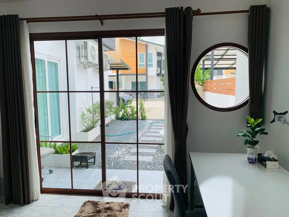 Modern home office with garden view through large window, stylish decor and natural light.