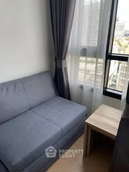 Cozy living room with a modern gray sofa and city view from the window.