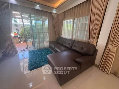 Spacious living room with elegant curtains and a cozy leather sofa, opening to a sunny patio.