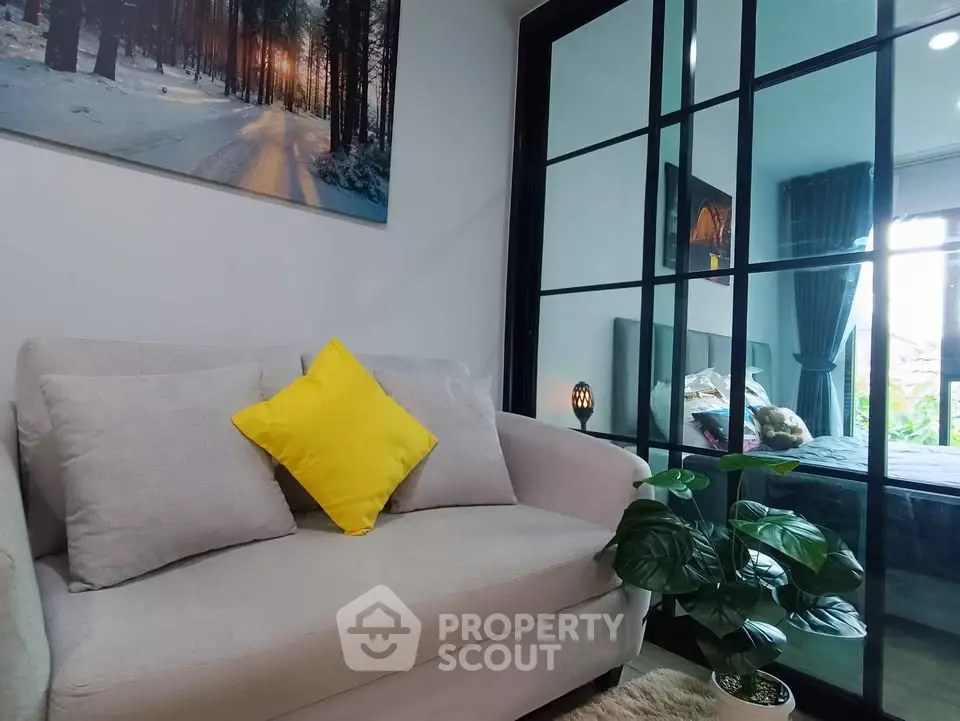 Stylish living room with cozy sofa and glass partition leading to a modern bedroom.