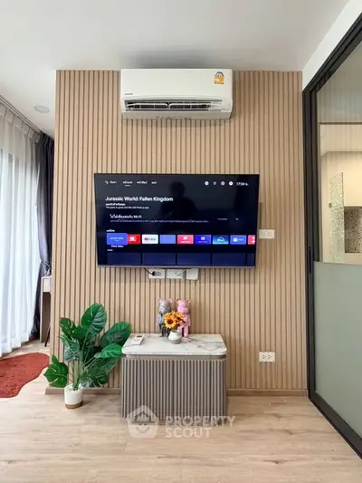 Modern living room with wall-mounted TV and air conditioning, featuring stylish decor and wooden paneling.