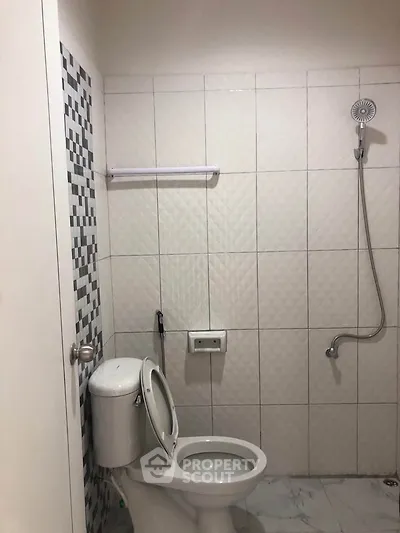 Modern bathroom with tiled walls and showerhead, featuring a sleek toilet design.