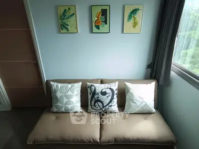 Cozy living room with stylish sofa and decorative pillows, complemented by modern wall art and natural light.