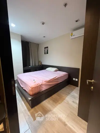 Cozy bedroom with modern furnishings and wooden flooring, featuring a comfortable bed and air conditioning.