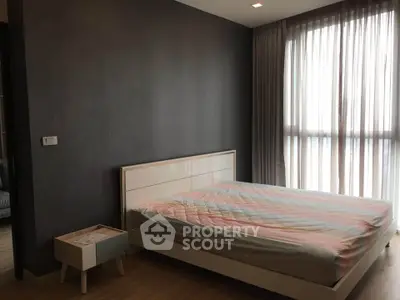 Modern bedroom with stylish bed and natural light through large window.