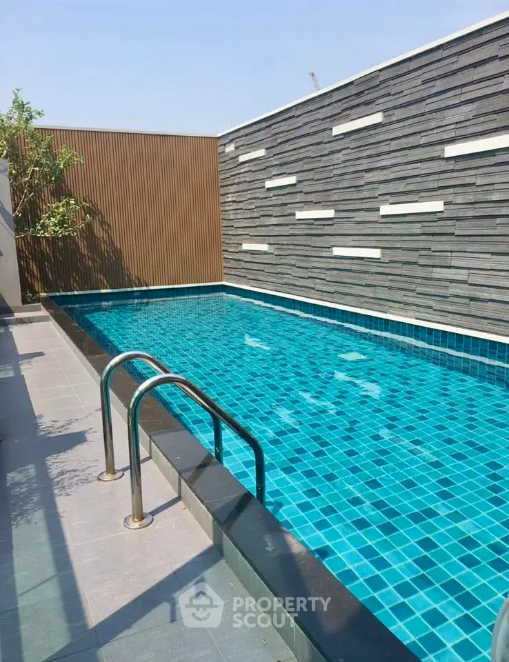 Luxurious modern swimming pool with sleek design and privacy wall, perfect for relaxation and leisure.