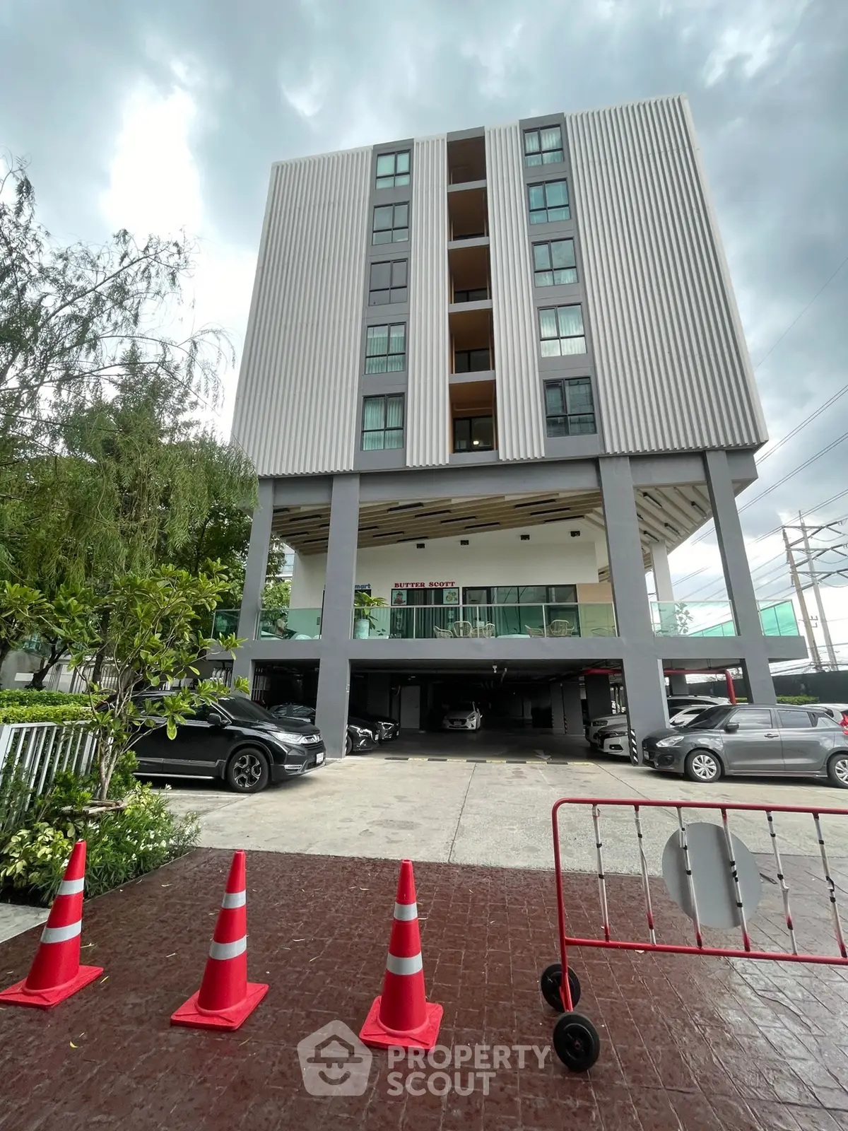 Modern multi-story building with parking area and sleek architectural design.