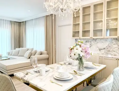 Luxurious open-plan living and dining area with elegant chandelier and marble accents.