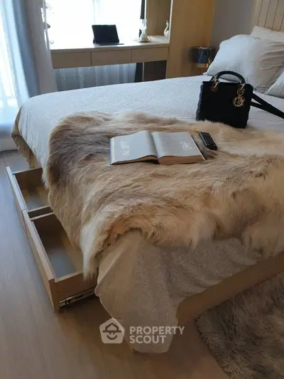 Luxurious bedroom with fur throw, elegant handbag, and open book on bed, showcasing modern design and comfort.