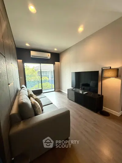 Modern living room with sleek furniture and large TV, featuring a cozy ambiance and natural light.