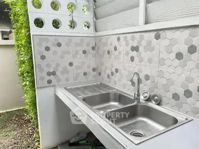 Modern outdoor kitchen sink with stylish hexagonal tiles and lush greenery