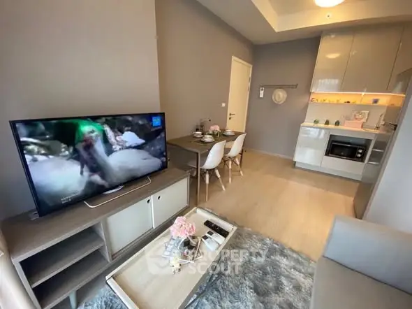 Modern living room with open kitchen, featuring sleek furniture and a cozy dining area.
