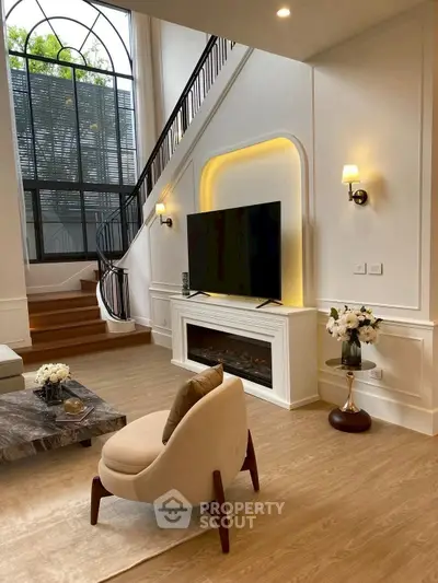 Luxurious living room with high ceilings, elegant staircase, and modern decor