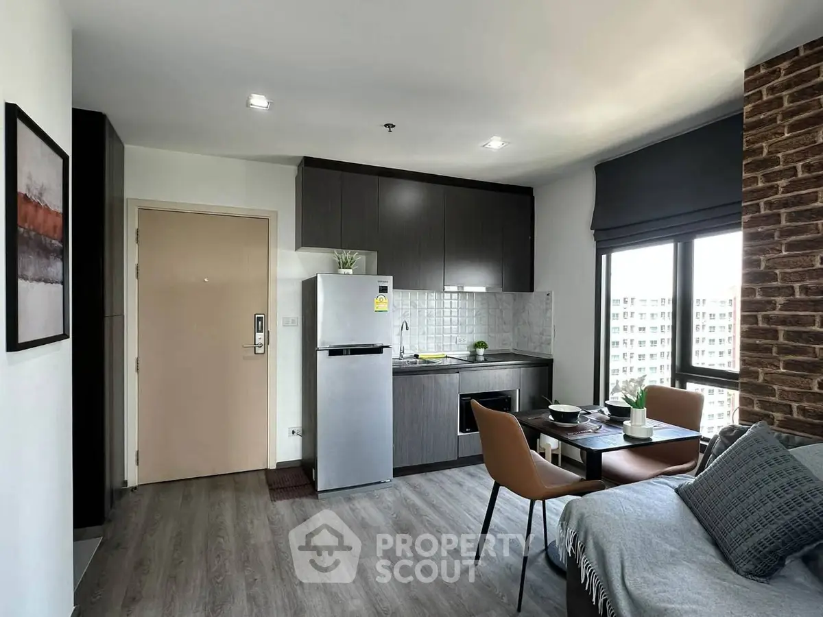 Modern studio apartment with sleek kitchen and cozy living area, featuring large window for natural light.