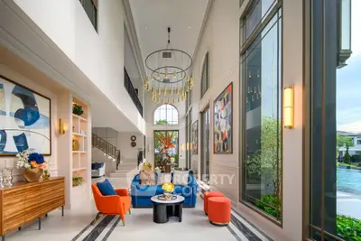 Luxurious living room with high ceilings, modern decor, and large windows overlooking a pool.