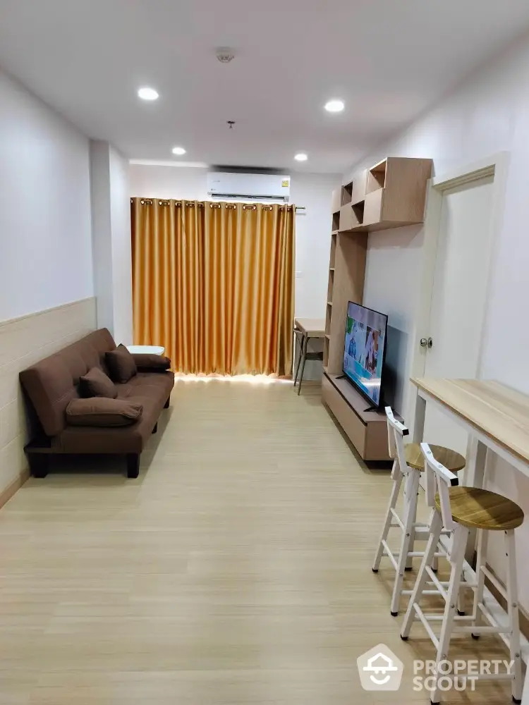 Modern living room with cozy sofa and entertainment unit, featuring stylish wooden flooring and bright curtains.