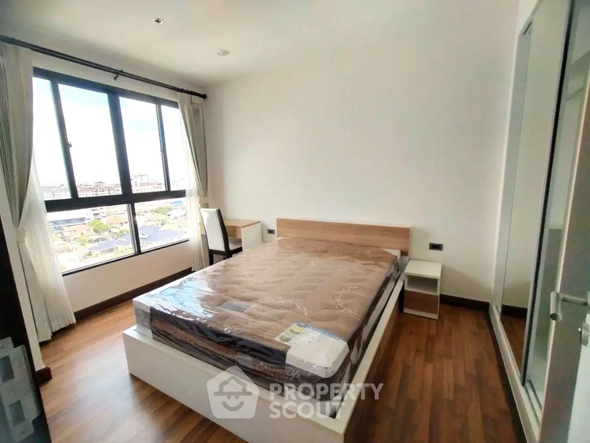 Spacious bedroom with large window offering stunning city views and modern furnishings.