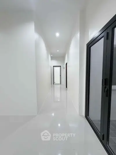 Sleek modern hallway with glossy white tiles and glass door, perfect for contemporary living.