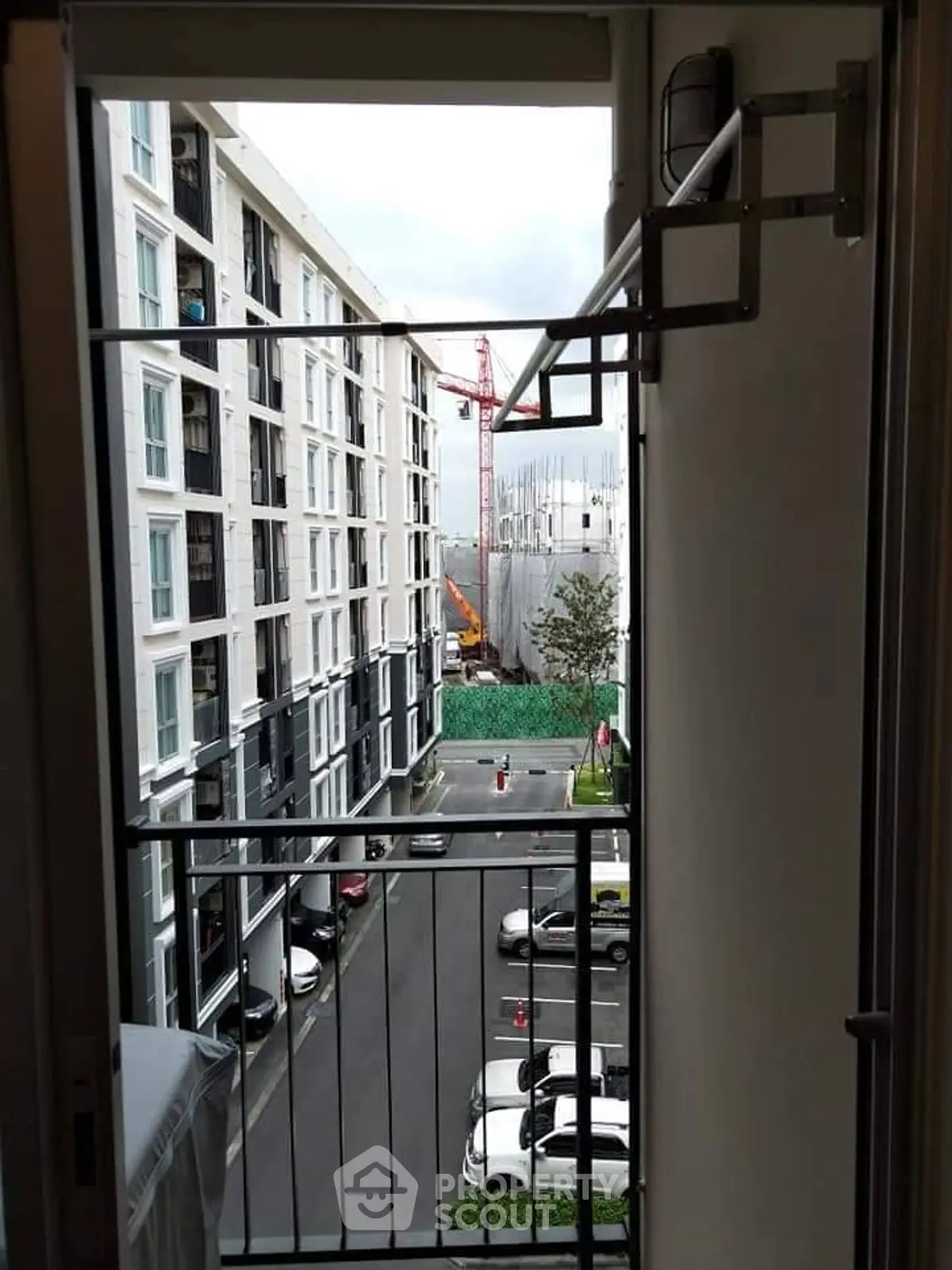 Urban apartment view with construction site and parked cars