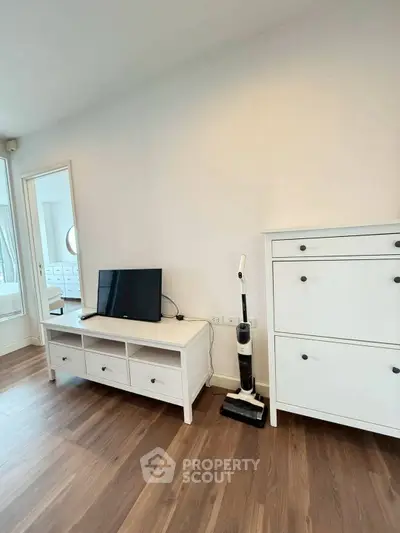 Modern living room with sleek white furniture and hardwood floors, featuring a stylish TV stand and storage cabinet.