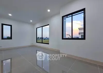 Spacious modern living room with large windows and stunning sunset view.