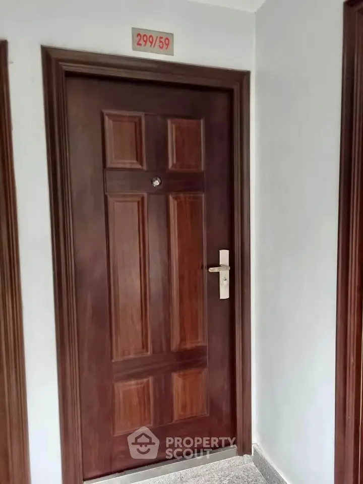 Elegant wooden apartment door with modern handle in a well-maintained hallway.