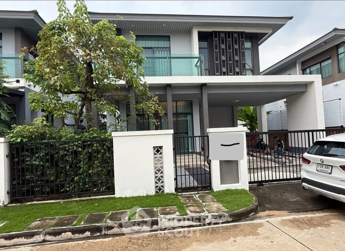 Modern two-story house with sleek design and spacious driveway in a suburban neighborhood.