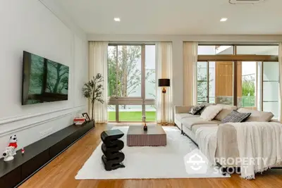 Luxurious modern living room with elegant decor and large windows offering garden views.