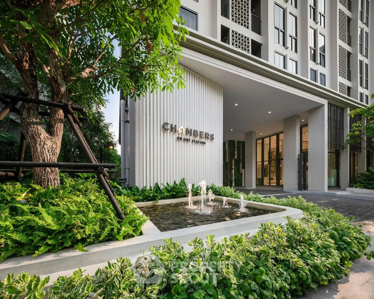 Modern building entrance with lush greenery and water feature