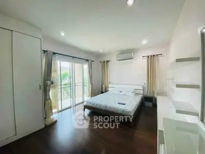 Spacious bedroom with balcony access and modern furnishings in a bright, airy apartment.