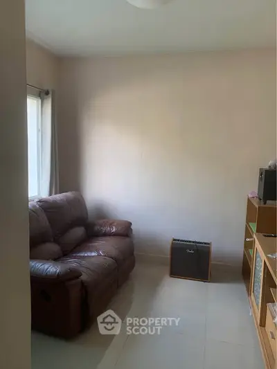 Cozy living room with leather sofa and natural light, perfect for relaxation.