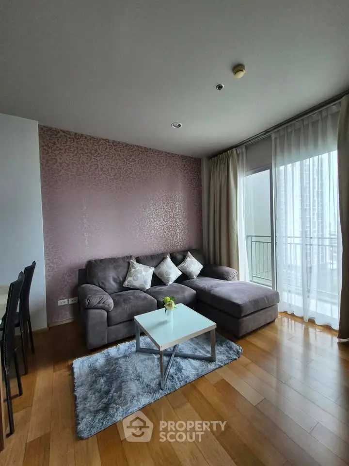 Modern living room with stylish decor and large windows offering natural light and city views.