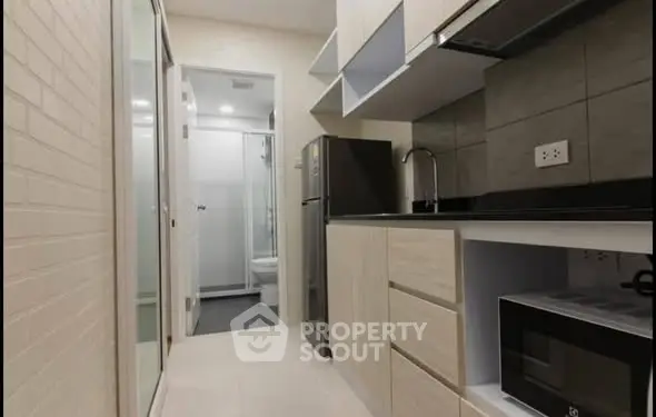 Modern compact kitchen with sleek cabinetry and appliances in a stylish apartment.