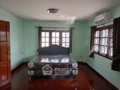 Spacious bedroom with large windows and air conditioning, featuring a stylish bed and polished wooden floors.