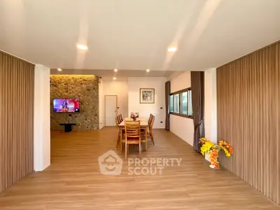 Spacious open-plan living and dining area with modern decor and wooden flooring.