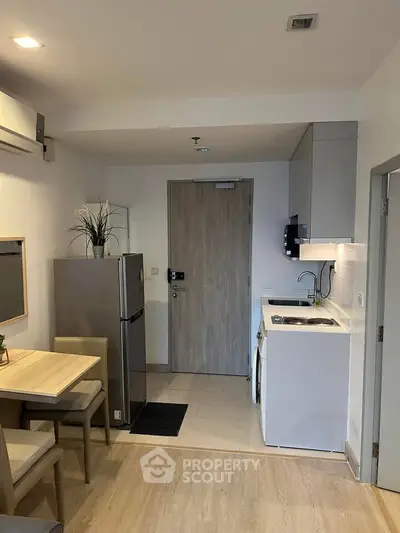 Modern compact kitchen with dining area and appliances in cozy apartment.