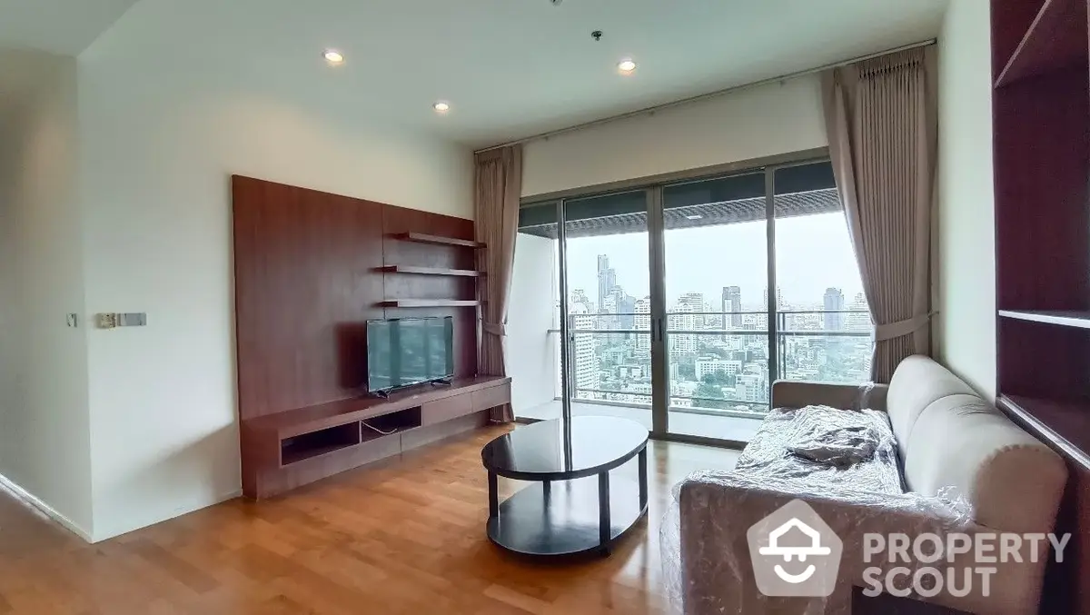 Spacious living room with polished hardwood floors, modern furniture, and large windows offering an expansive city view, perfect for urban living.